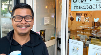 ian abadiano from coffee mentality standing outside his cafe holding a cup of coffee